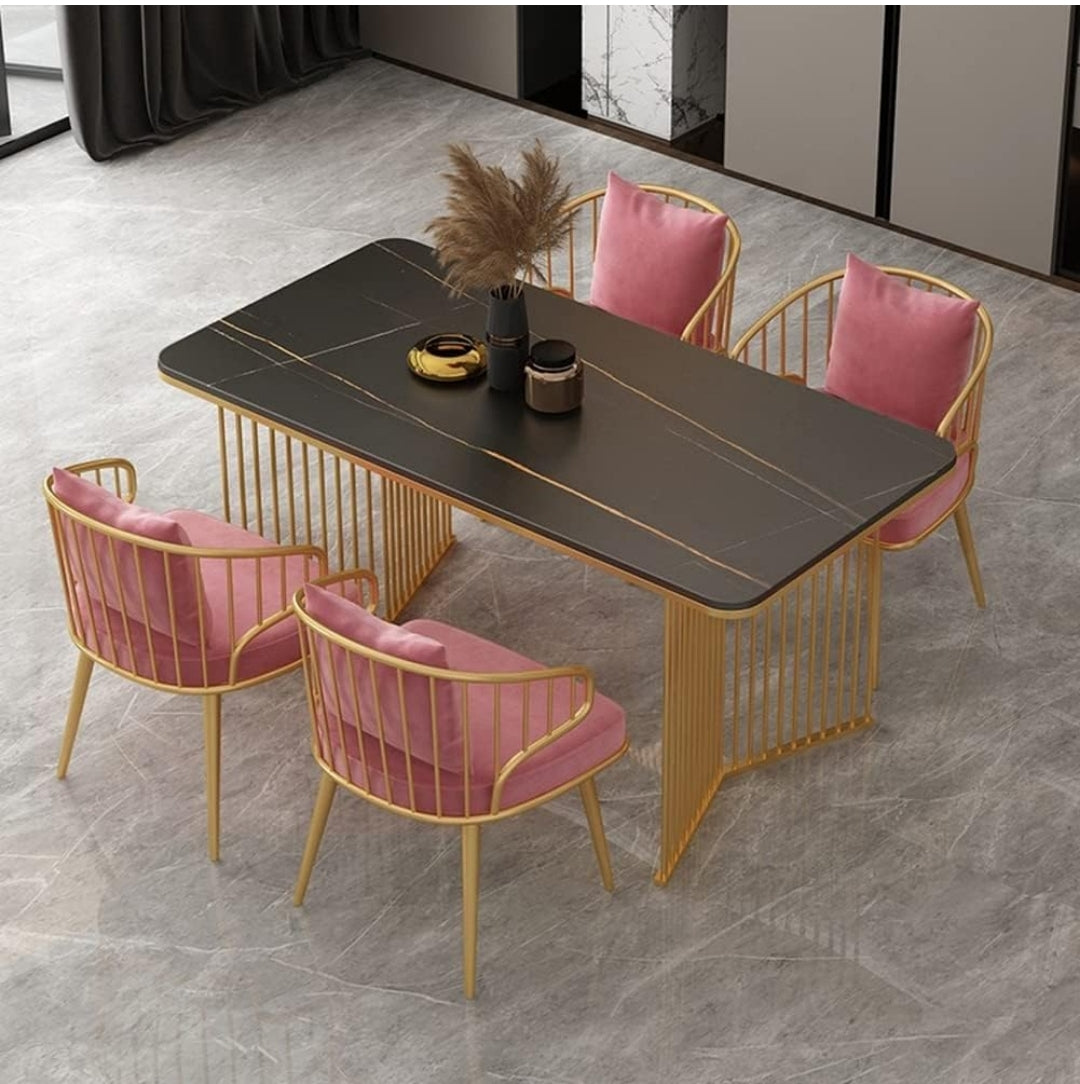 Mesa de lujo base dorada con superficie negra y sillas rosas en sala moderna
