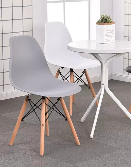 Silla de comedor moderna minimalista gris con patas de madera junto a una mesa blanca redonda